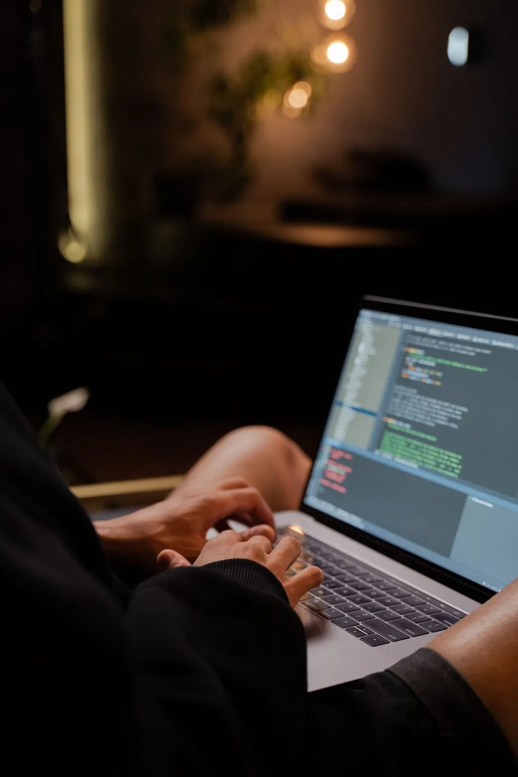 Person programmiert abends auf einem Laptop